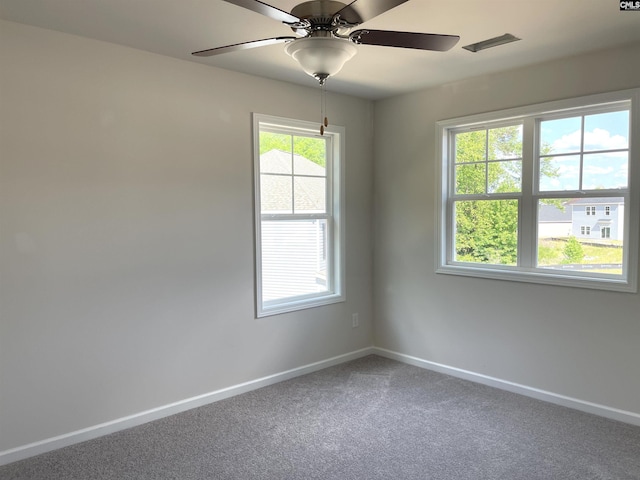 empty room with carpet, visible vents, baseboards, and ceiling fan