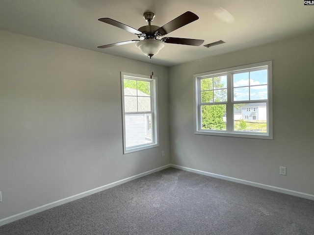 carpeted spare room with ceiling fan and baseboards