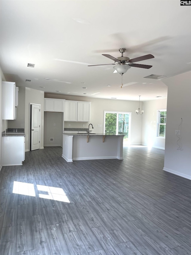 kitchen with dark wood-style floors, a ceiling fan, open floor plan, white cabinetry, and a kitchen bar