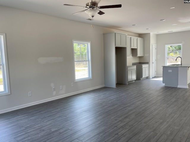 unfurnished living room featuring dark wood-style floors, plenty of natural light, and a sink