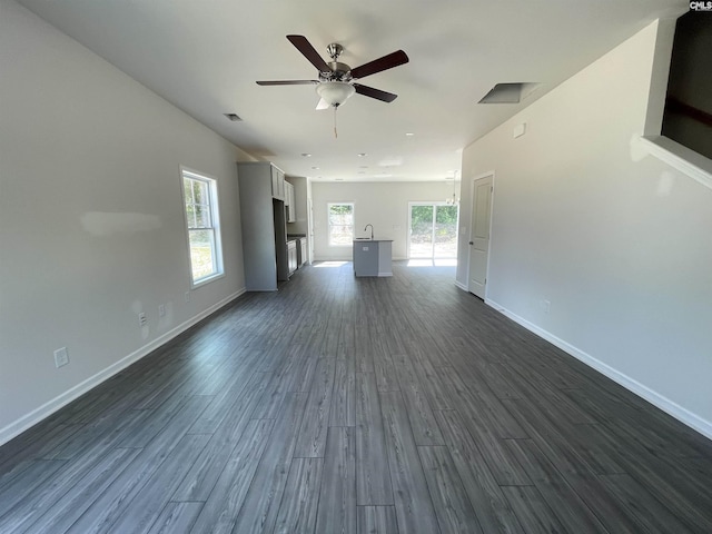 unfurnished living room featuring baseboards, visible vents, dark wood finished floors, a ceiling fan, and a sink