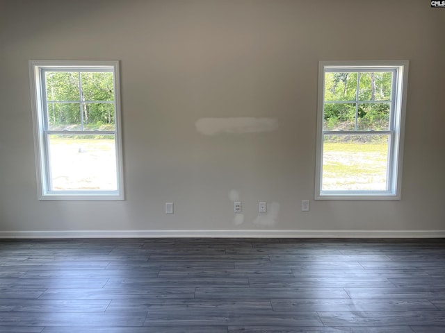 spare room featuring dark wood-style floors, plenty of natural light, and baseboards