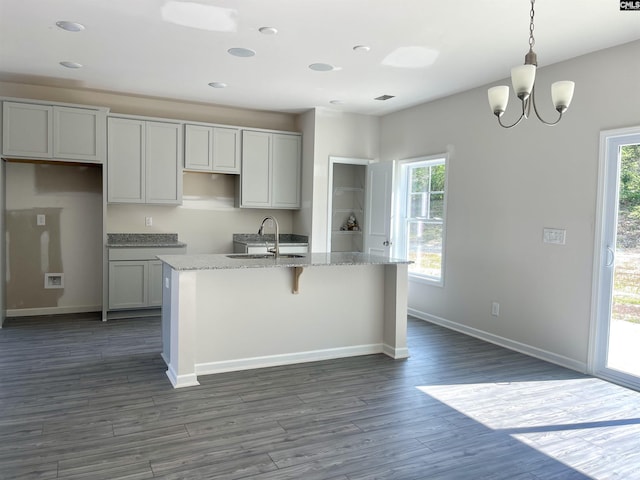 kitchen with a wealth of natural light, a center island with sink, dark wood-style flooring, and a sink