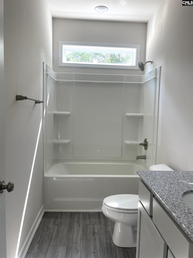 bathroom featuring a wealth of natural light, tub / shower combination, toilet, and wood finished floors