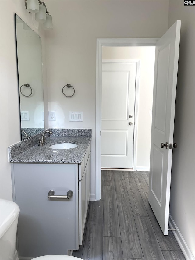 bathroom featuring baseboards, wood finished floors, and vanity