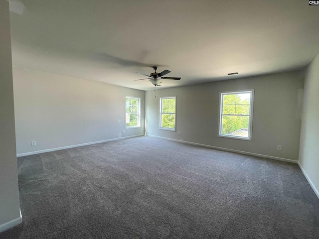 carpeted empty room with visible vents, a wealth of natural light, and baseboards