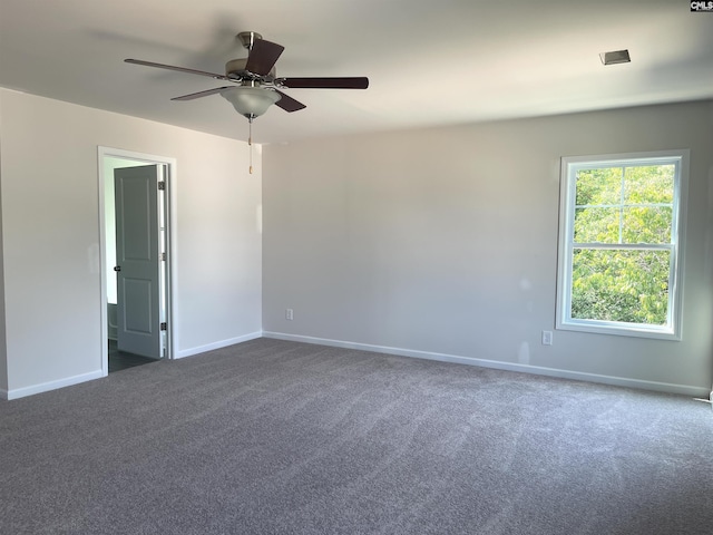 empty room with dark carpet, a ceiling fan, and baseboards