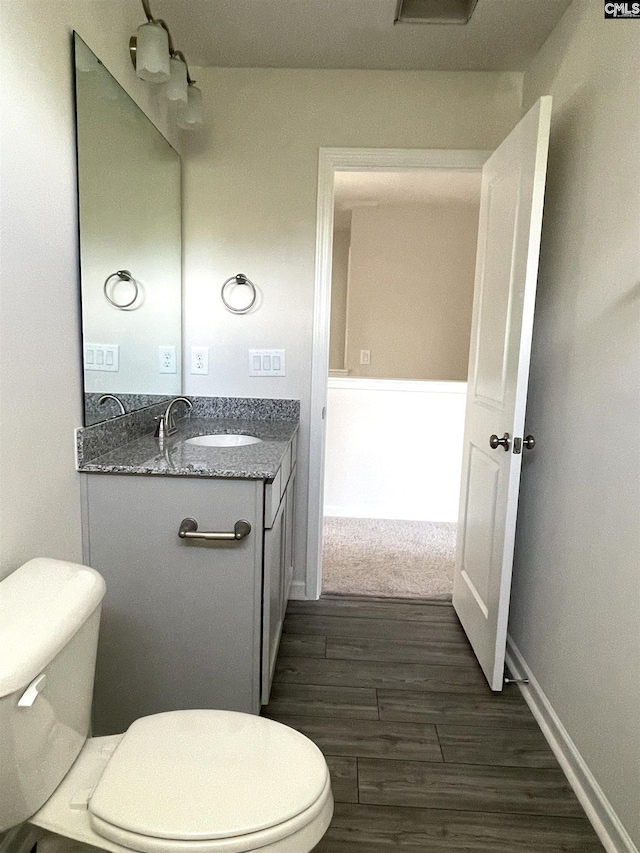 bathroom with toilet, baseboards, wood finished floors, and vanity