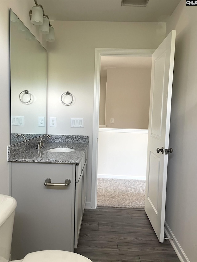 bathroom featuring toilet, baseboards, wood finished floors, and vanity