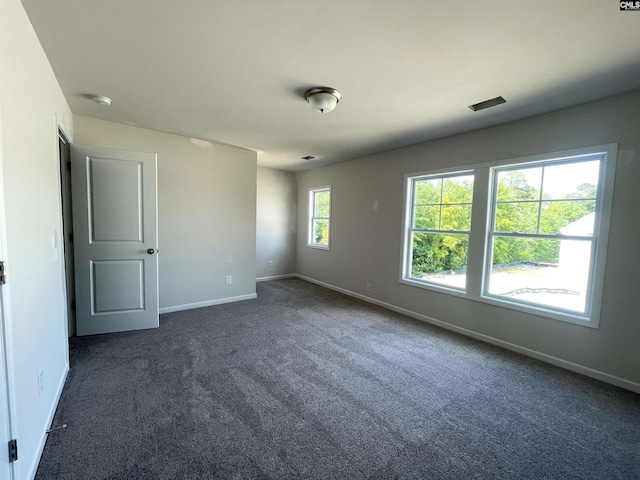 empty room with dark carpet and baseboards