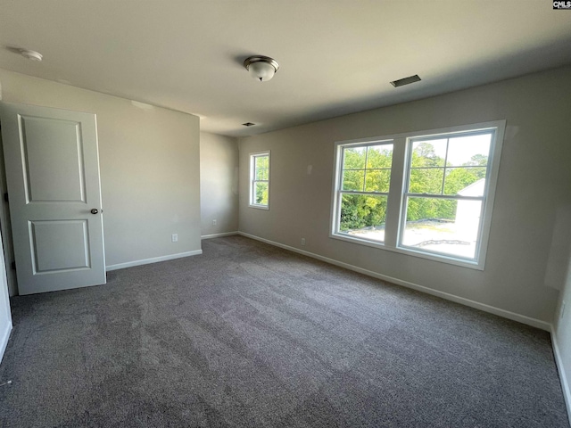 empty room with dark carpet and baseboards