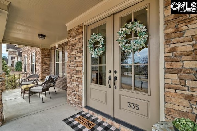 property entrance with french doors, brick siding, and a porch