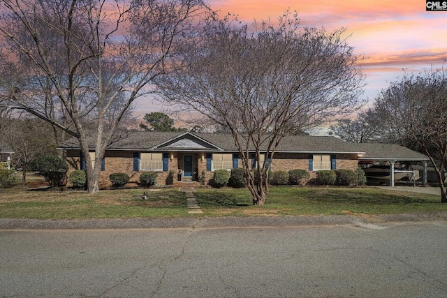 view of front of property with brick siding, an attached carport, and a front yard