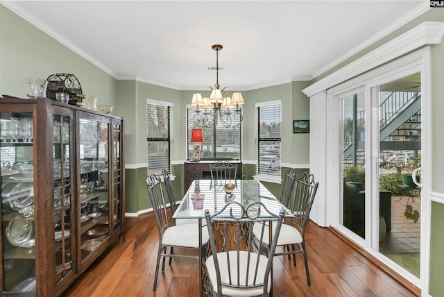 dining area featuring baseboards, visible vents, ornamental molding, dark wood-type flooring, and a chandelier