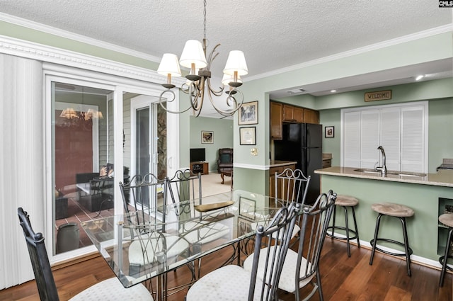 dining space with a textured ceiling, dark wood-type flooring, baseboards, ornamental molding, and an inviting chandelier