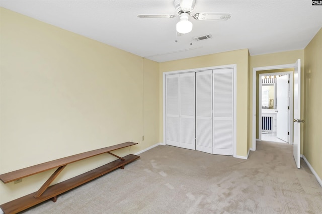 unfurnished bedroom featuring a closet, visible vents, a ceiling fan, light carpet, and baseboards