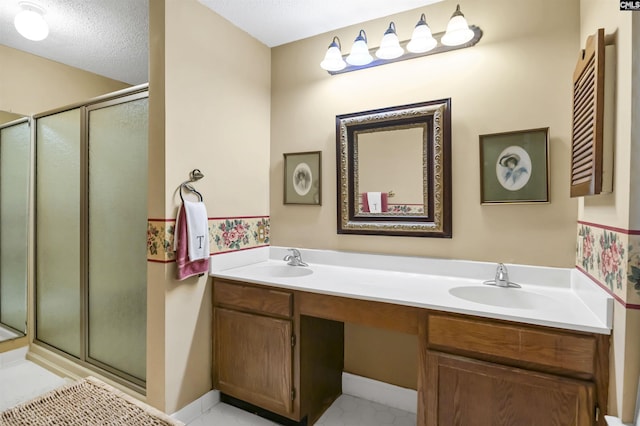 bathroom featuring double vanity, a shower stall, a textured ceiling, and a sink