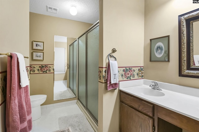 bathroom featuring a textured ceiling, toilet, vanity, visible vents, and a shower stall