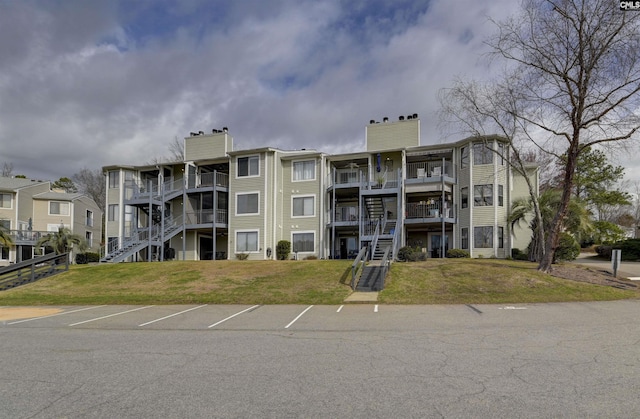 view of building exterior featuring stairs and uncovered parking