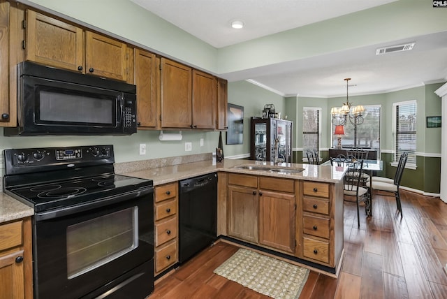 kitchen featuring dark wood-style flooring, visible vents, brown cabinetry, a peninsula, and black appliances