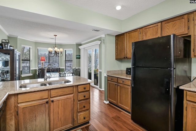 kitchen with visible vents, brown cabinetry, dark wood-style floors, freestanding refrigerator, and a sink