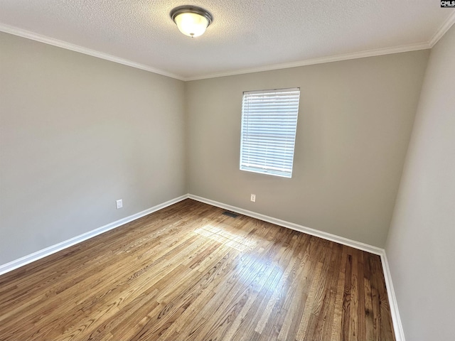 unfurnished room with a textured ceiling, crown molding, wood finished floors, and baseboards