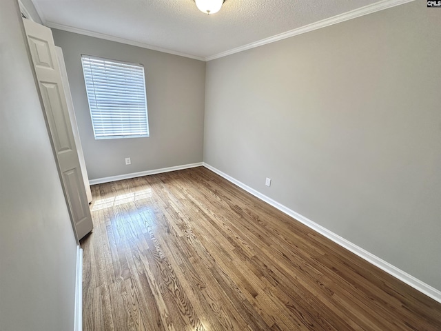 spare room featuring crown molding, a textured ceiling, baseboards, and wood finished floors