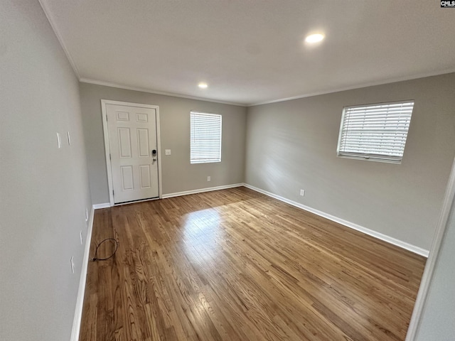 empty room featuring crown molding, baseboards, and wood finished floors