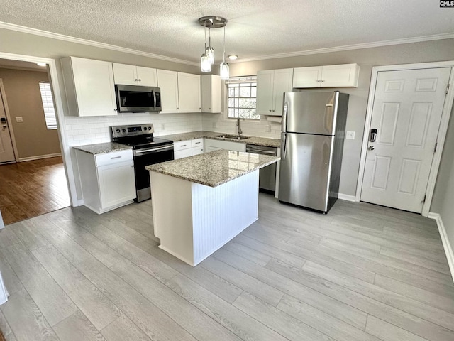 kitchen with appliances with stainless steel finishes, light wood-style floors, white cabinetry, a sink, and light stone countertops