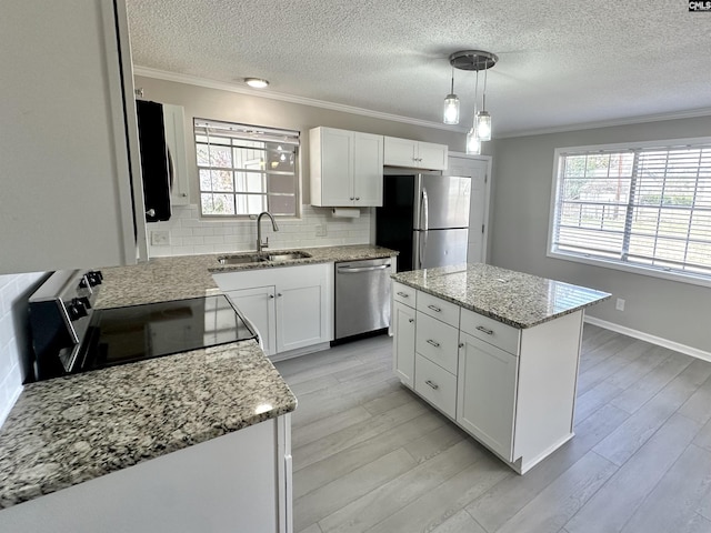 kitchen with light wood-style flooring, appliances with stainless steel finishes, a sink, and ornamental molding