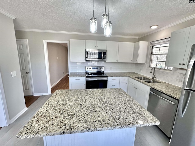 kitchen featuring light wood finished floors, appliances with stainless steel finishes, a sink, and a center island