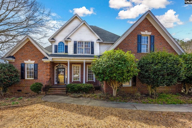 traditional-style home with crawl space, brick siding, covered porch, and roof with shingles