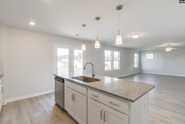 kitchen with dishwasher, light wood-style flooring, light stone counters, and a sink