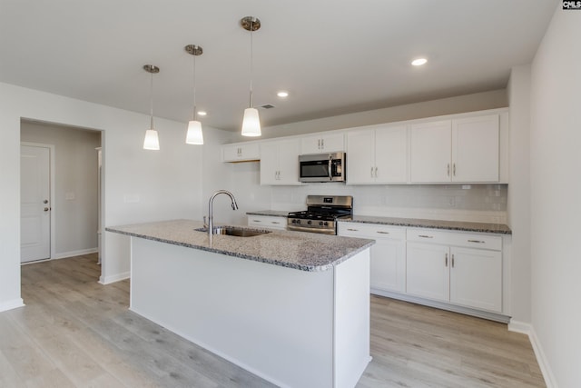 kitchen with stainless steel appliances, a sink, light wood-style flooring, and white cabinets