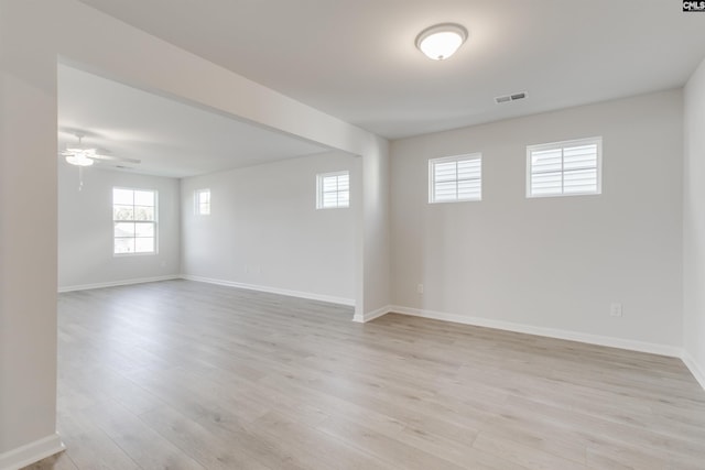 unfurnished room with light wood-type flooring, visible vents, and baseboards