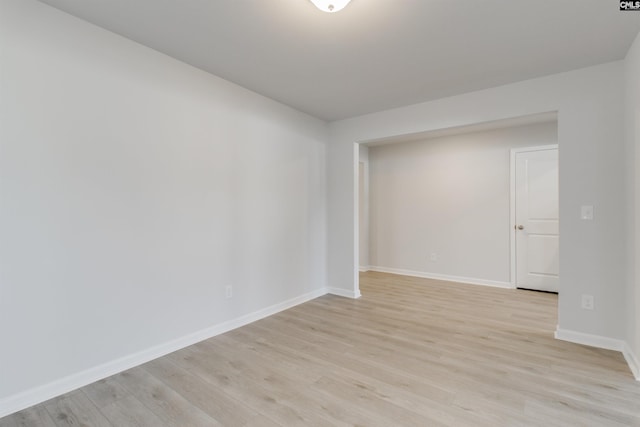 spare room with baseboards and light wood finished floors