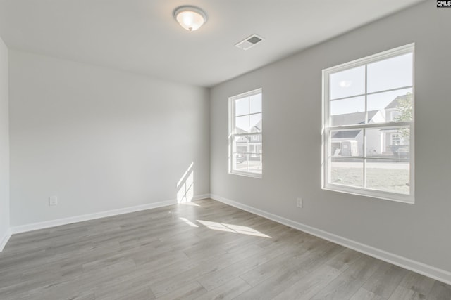 spare room featuring visible vents, light wood-style flooring, and baseboards