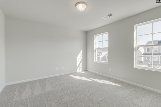 carpeted spare room featuring baseboards and visible vents