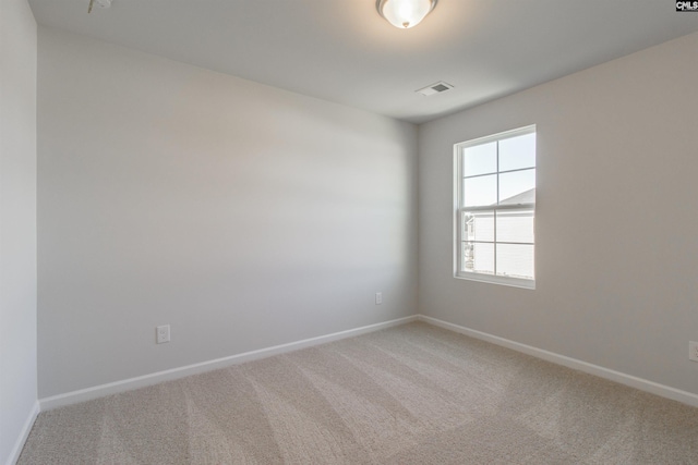 empty room featuring light carpet, visible vents, and baseboards