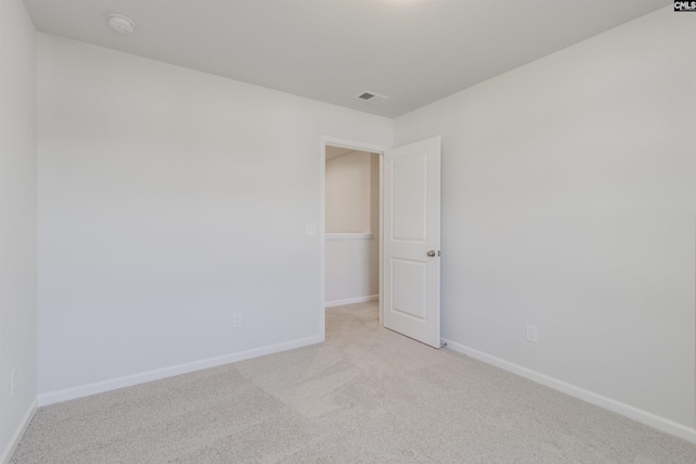 empty room with visible vents, baseboards, and light colored carpet