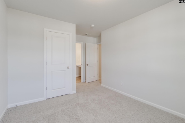 unfurnished bedroom featuring light colored carpet, visible vents, and baseboards