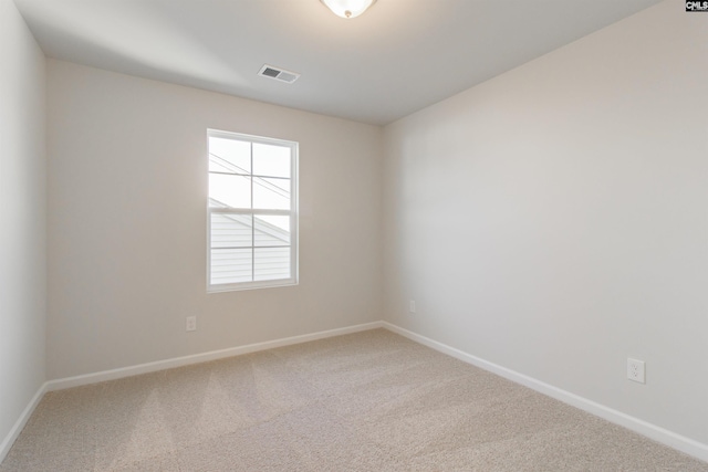 empty room featuring carpet, visible vents, and baseboards