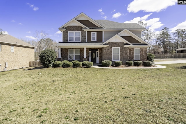 craftsman house with brick siding, fence, and a front lawn