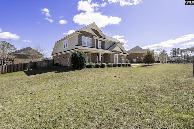 view of front of house featuring a front lawn, fence, and brick siding