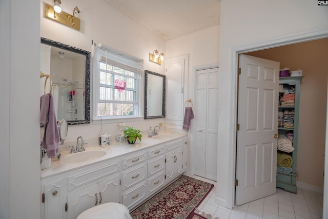 full bath featuring double vanity, a closet, a sink, and tile patterned floors