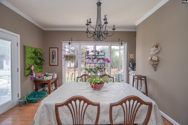 dining area with baseboards, a notable chandelier, ornamental molding, and wood finished floors