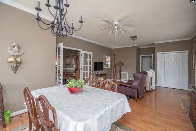 dining area with light wood-style flooring, crown molding, and french doors