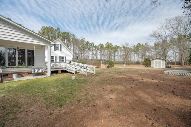 view of yard featuring a storage shed, a wooden deck, and an outbuilding