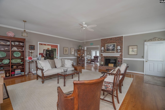 living room with a brick fireplace, ceiling fan, ornamental molding, and wood finished floors