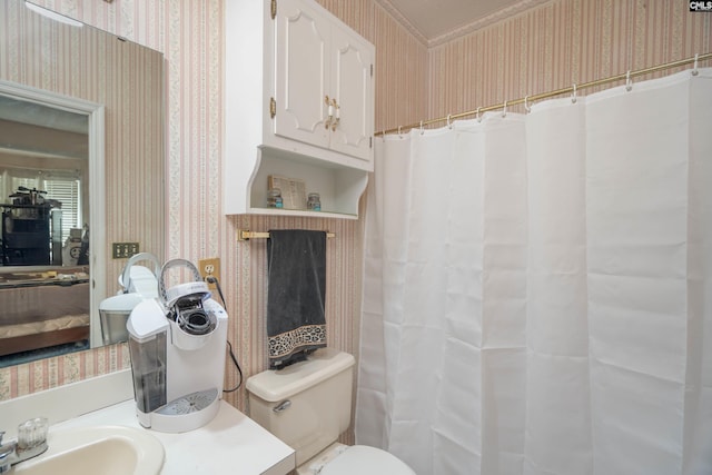 bathroom featuring vanity, toilet, and wallpapered walls